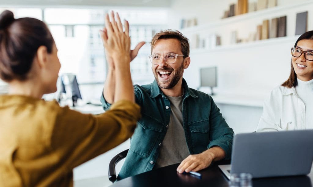 Smiling man giving a high five in a modern office environment.